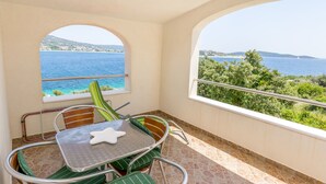Ein Balkon mit Tisch und Stühlen, einer Seestern-Dekoration und Blick auf das Meer und die Hügel.