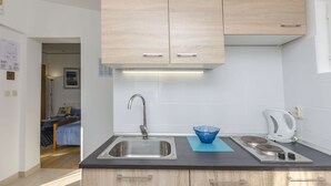 Una cocina moderna con un lavamanos de acero inoxidable, armarios de madera, una tetera y un tazón azul sobre la encimera.