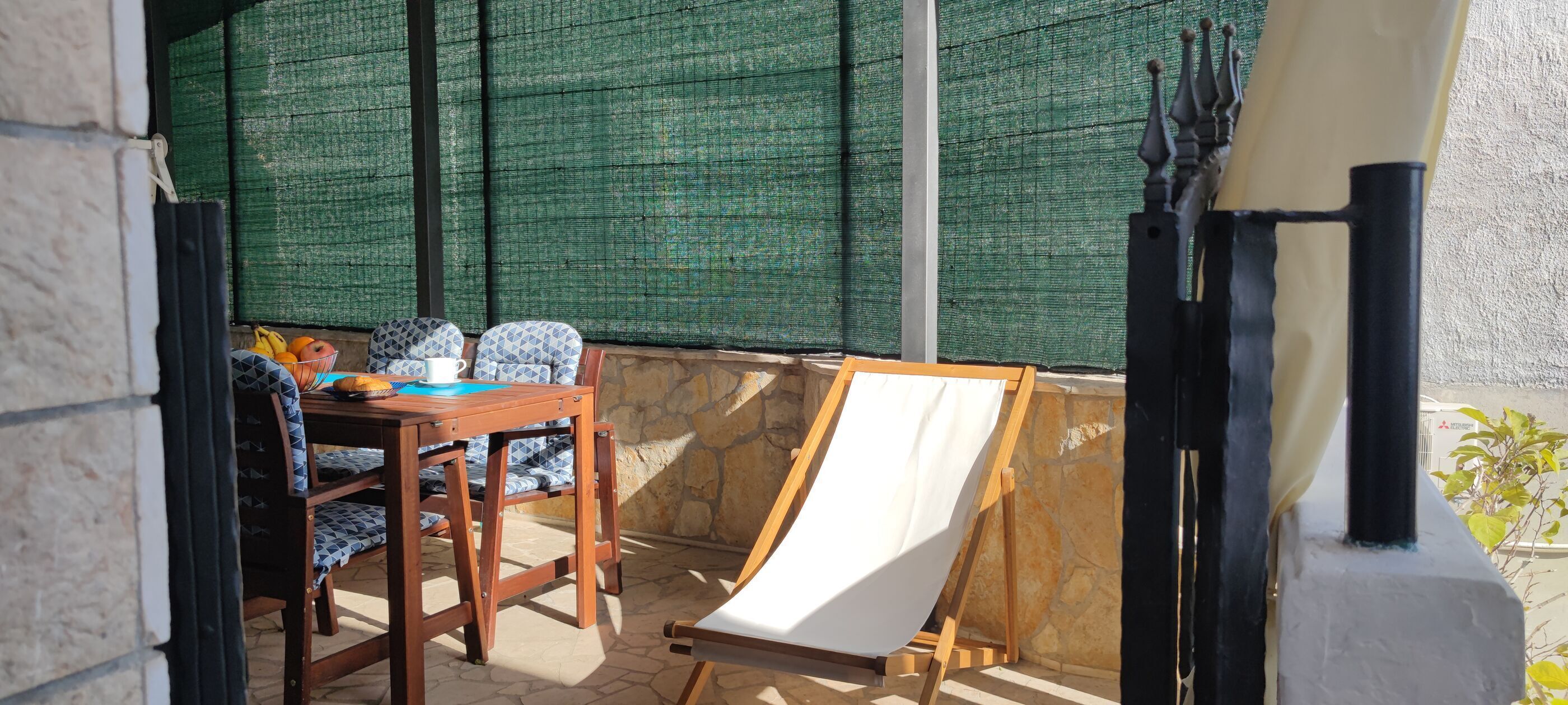 Un espace patio aménagé avec une table et des chaises, un chevalet en bois et un mur en treillis vert.