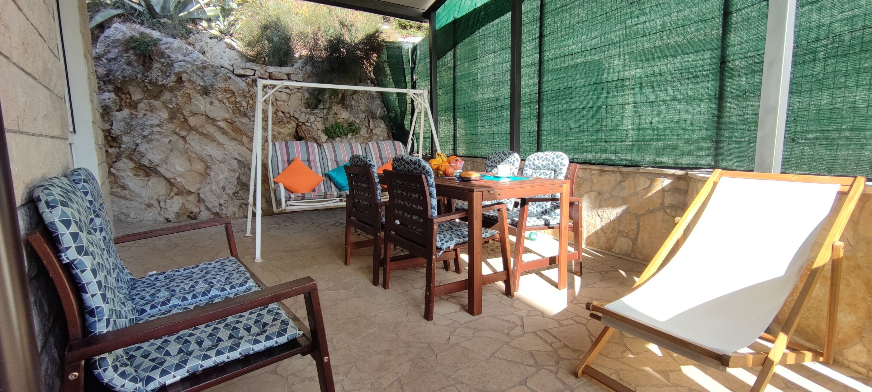Un patio con un columpio, una mesa y sillas, y un caballete.
