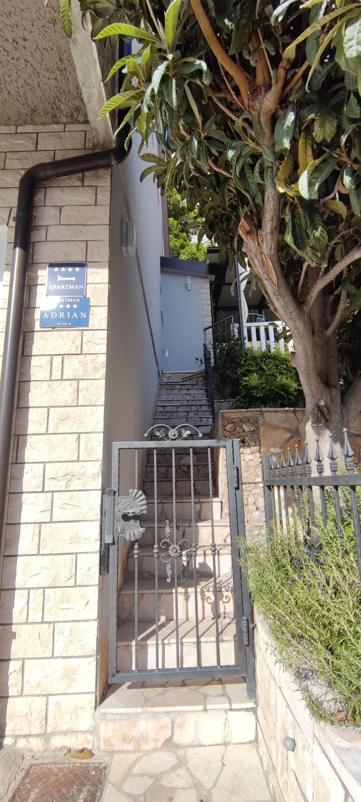 A gated entrance with a sign indicating an apartment named "Adrian" with a 4-star rating.