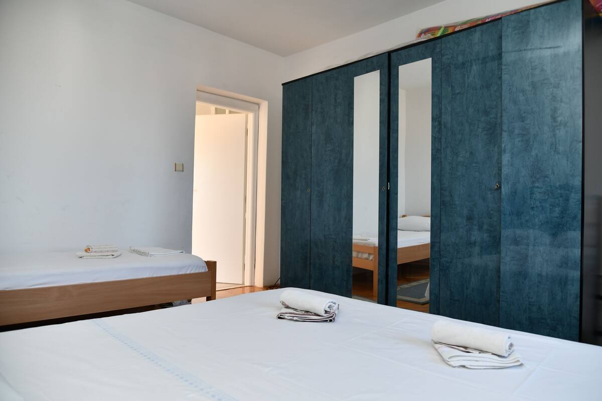 A bedroom with a wooden bed, a blue wardrobe, and a white door.