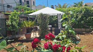 A garden with a gazebo, potted plants, and red roses. - Apartments Valerija (Supetar)