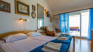 A hotel room with two beds, a balcony with a view, and a dining area. - Apartments Dubravka (Crikvenica)