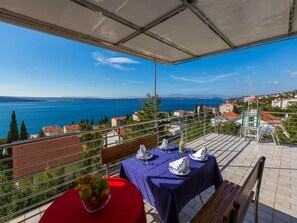 Ein Balkon mit Esstisch, der auf einen malerischen See und ferne Berge blickt.