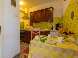 A small kitchen with wooden cabinets, a checkered tablecloth, and basic appliances. - Apartments Dubravka (Krk)