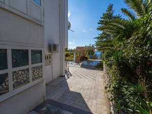 A courtyard with a pool, stone walls, and a view of the sea. - Apartments Dubravka (Krk)