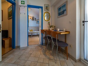 Une chambre d’hôtel dotée d’un coin repas comprenant une table en bois, deux chaises et une petite table sur laquelle est posé un vase de fleurs.