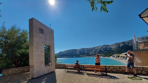 Un espacio con bancos de piedra y vistas a un lago y montañas.