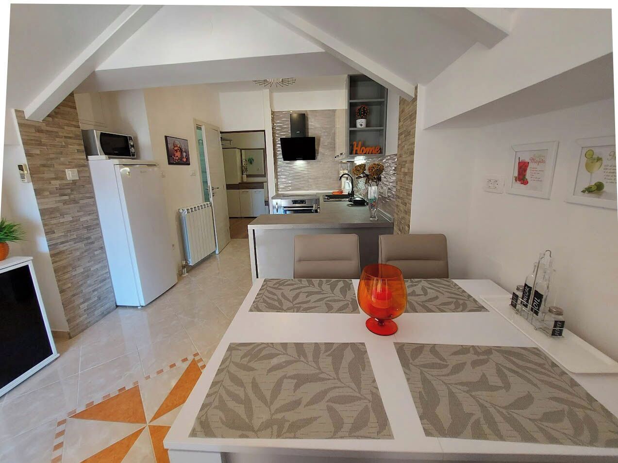 A modern kitchen with a microwave, refrigerator, and a dining area with a table and chairs.