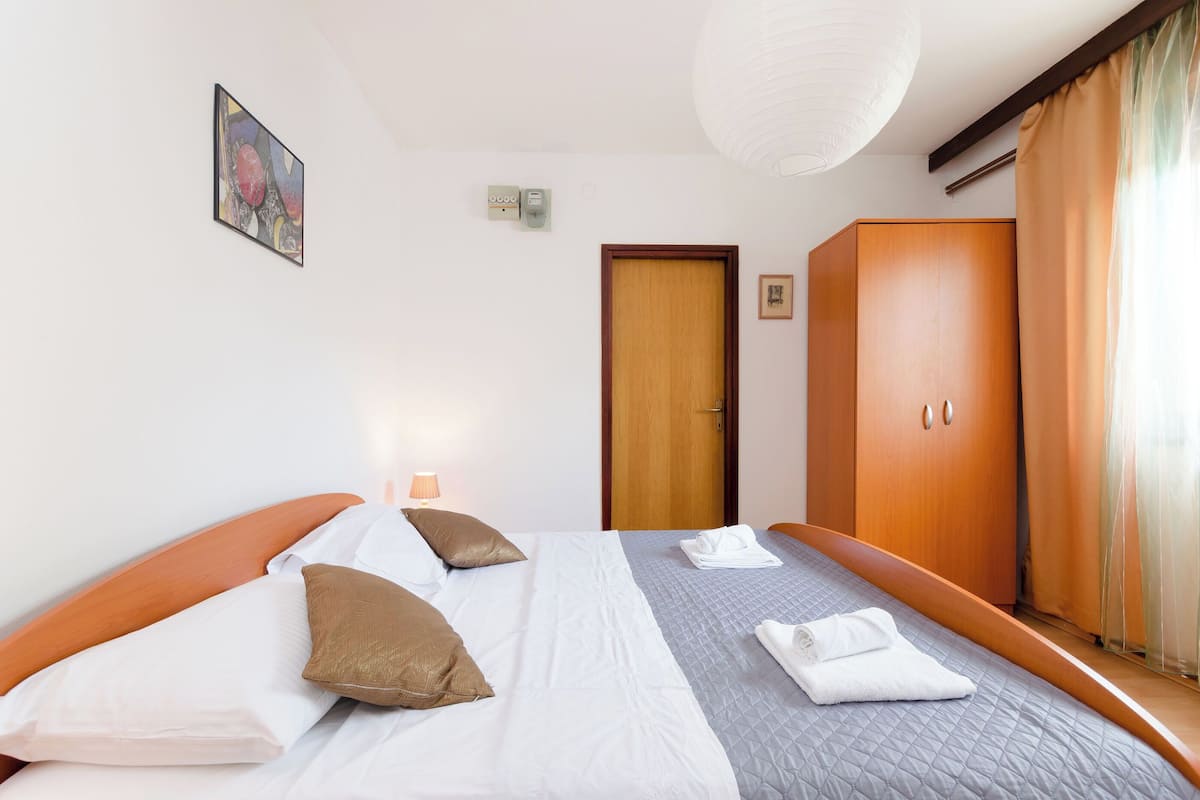 A hotel room with a bed, a wardrobe, a door, and a painting on the wall.