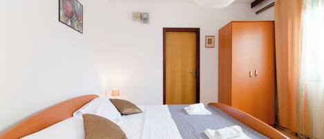 A hotel room with a bed, a wardrobe, a door, and a painting on the wall.