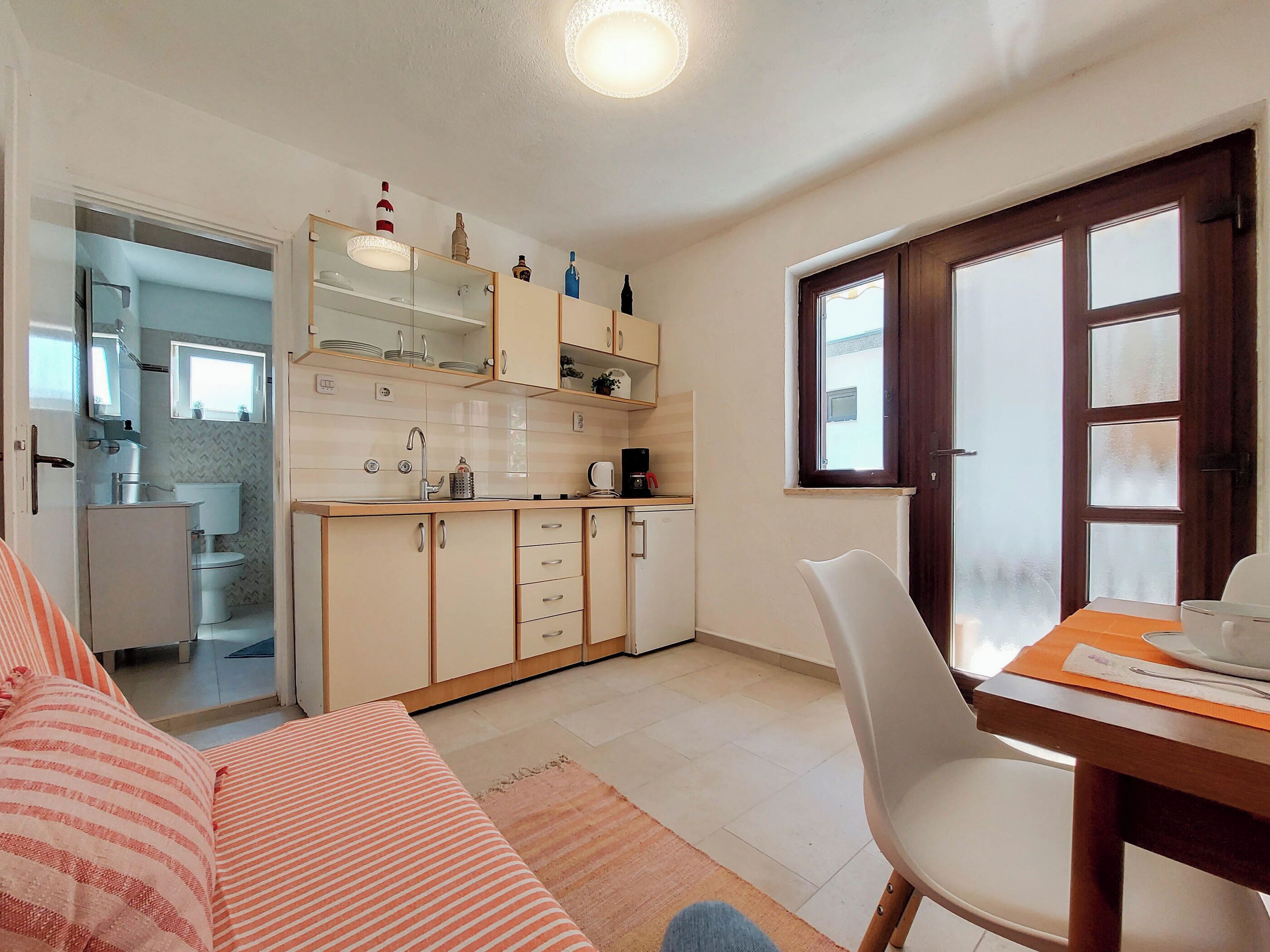 Un espacio habitable compacto con kitchenette, un comedor con mesa y silla, y un sofá.