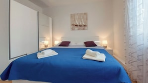 Une chambre d’hôtel avec un grand lit, deux lampes de chevet, un miroir et un tableau au mur.