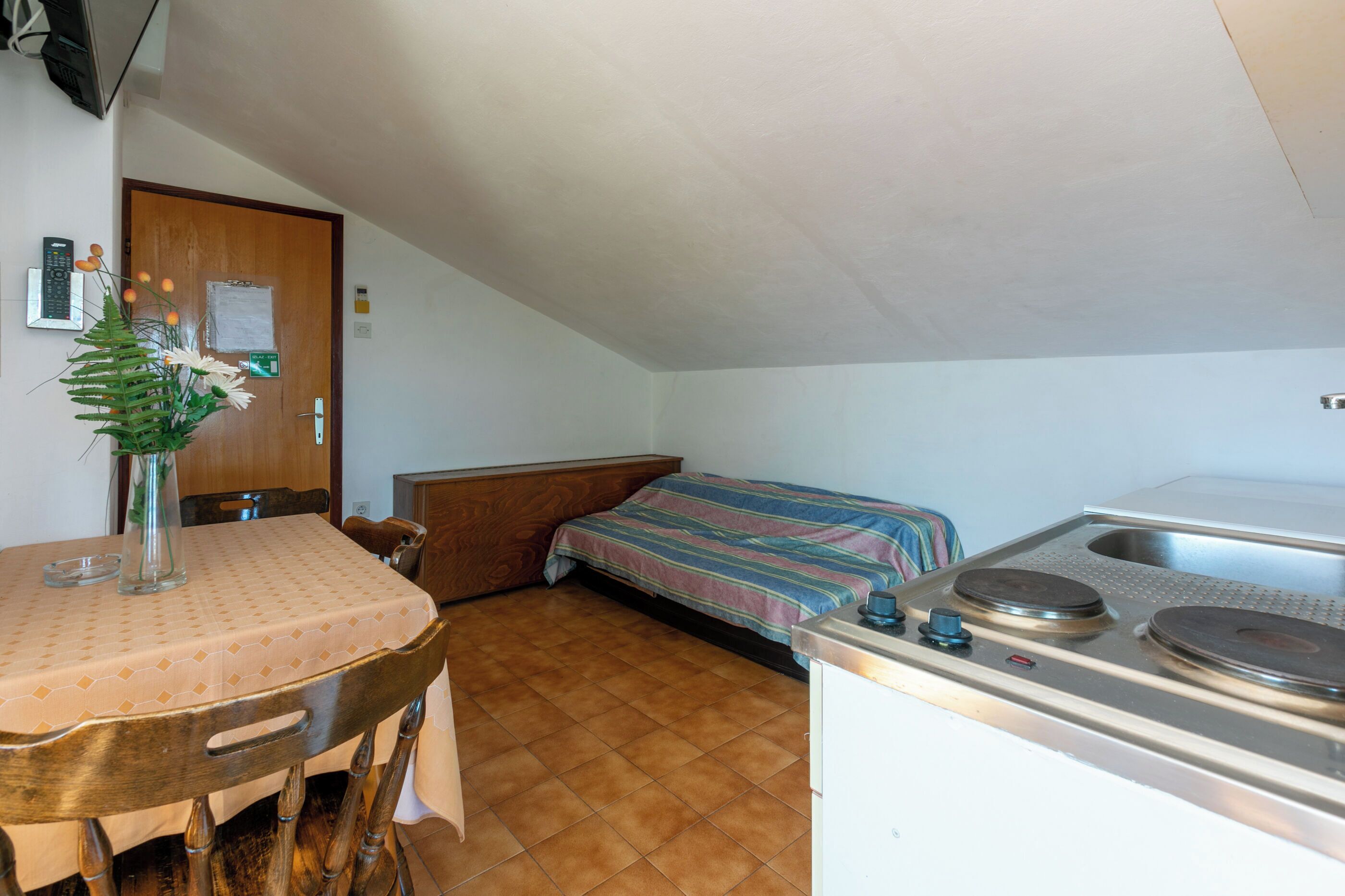 A compact kitchen with a stove, sink, and a small dining area with a table and chairs.