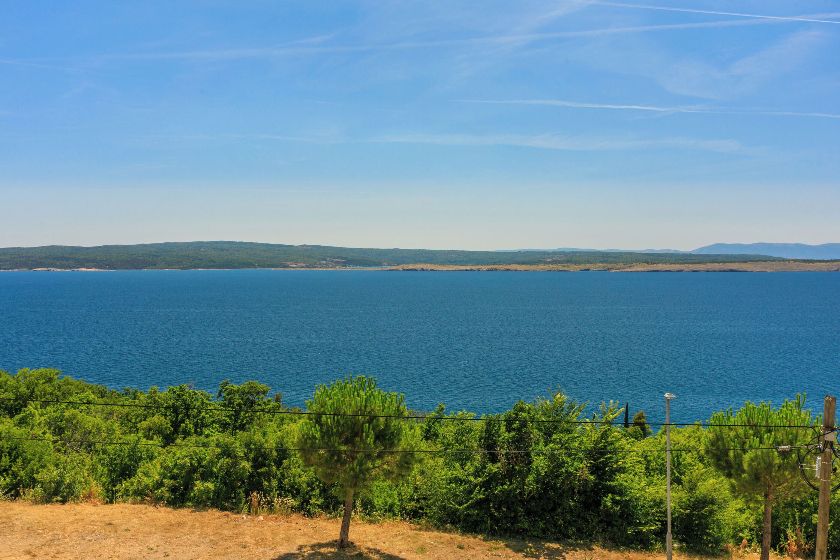 A coastal landscape with a clear view of the sea and distant hills.