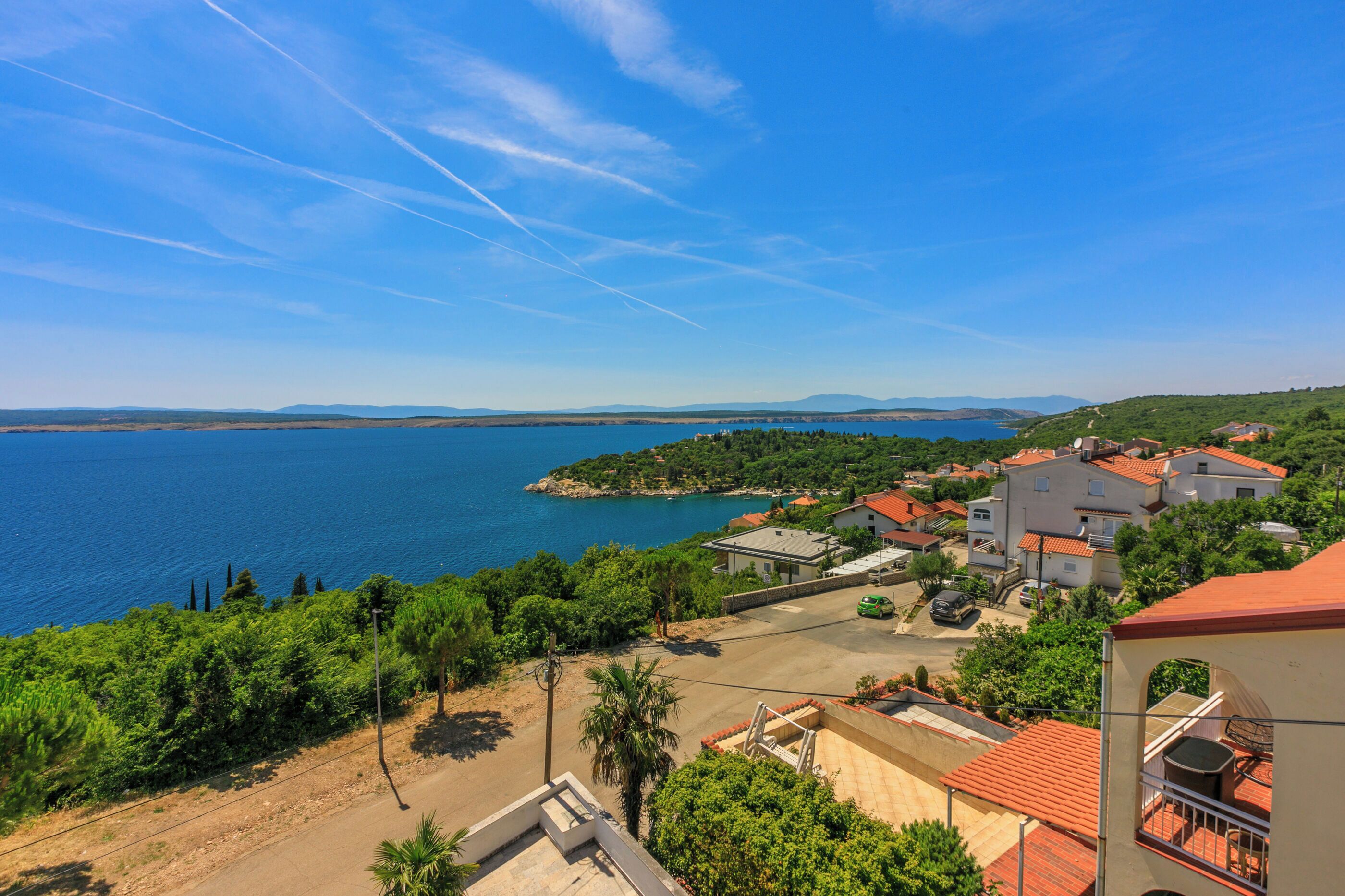 A coastal town with buildings, a clear blue sky, and a large body of water.