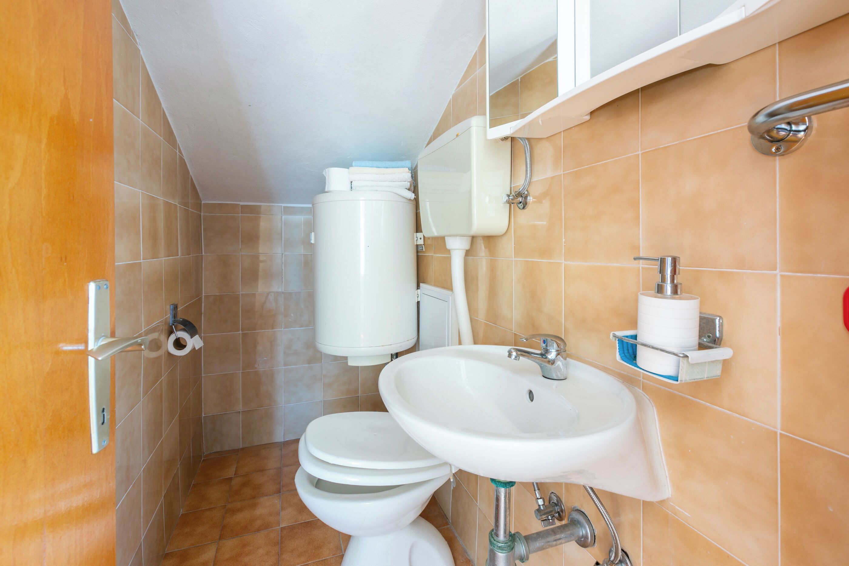 Un bagno con un WC, lavandino e mobile contenitore.