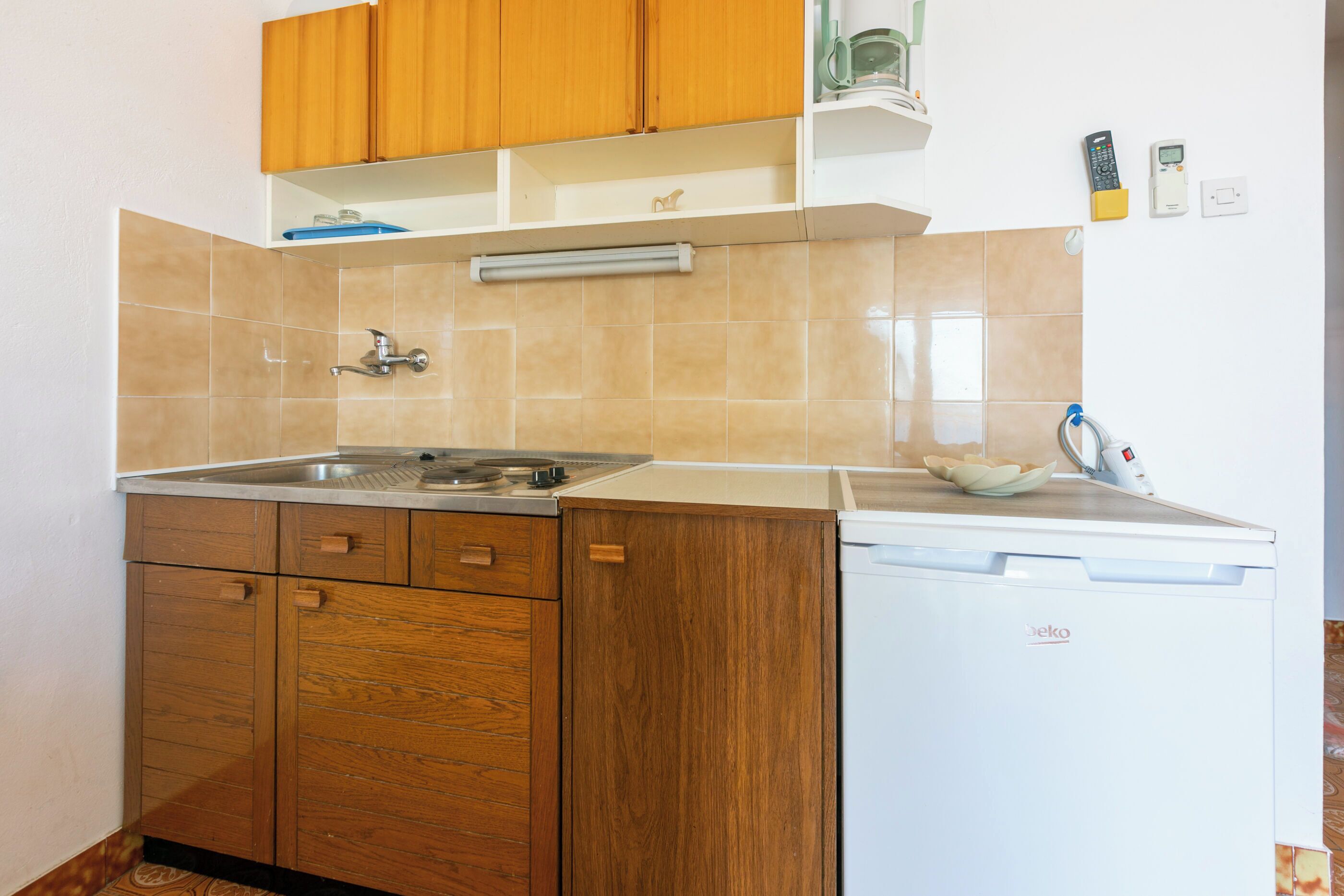 Una cocina compacta con armarios de madera, un lavaplatos empotrado y un lavavajillas blanco.