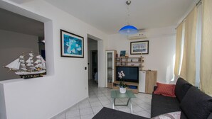 A living room with a model ship, a sofa, a TV stand, and a dining area. - Apartments Neno (Primosten)