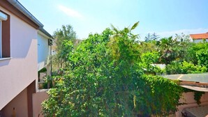 A residential area with a house partially obscured by dense greenery. - Apartments Ivan Marina (Krk)