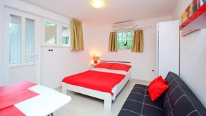 A bedroom with a bed, a sofa, a table, and a window with curtains. - Apartments Ivan Marina (Krk)