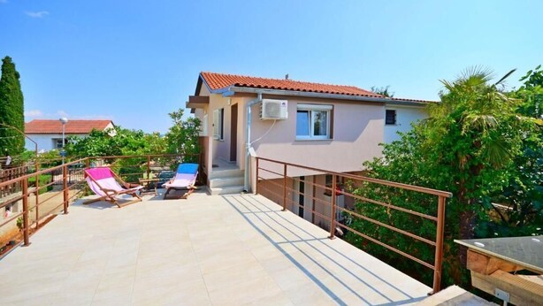 A two-story building with a red-tiled roof, a small balcony with a metal railing, and a pool area with lounge chairs. - Apartments Ivan Marina (Krk)