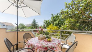 A round table with a floral tablecloth, surrounded by four chairs, on a balcony with a white umbrella. - Apartments Bella Vista (Srima)