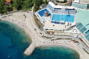 Eine Vogelperspektive einer Küstenlandschaft mit Schwimmbad, Strand und angrenzenden Gebäuden.