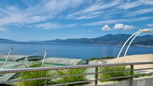 A coastal view with a clear sky, a body of water, and distant mountains. - Apartments Marija (Rijeka)