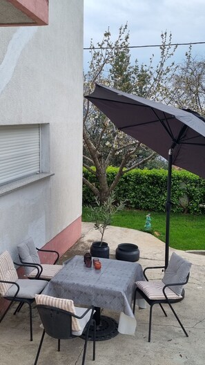 An outdoor patio with a table, chairs, and a large umbrella.