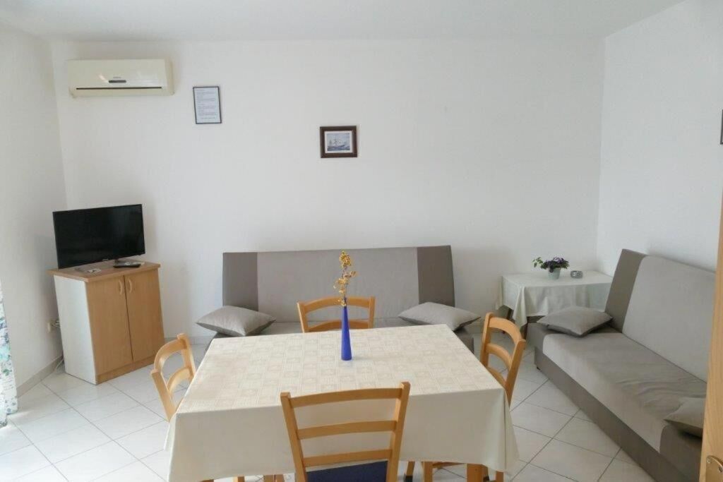 A dining area with a table, chairs, a television, and a sofa.