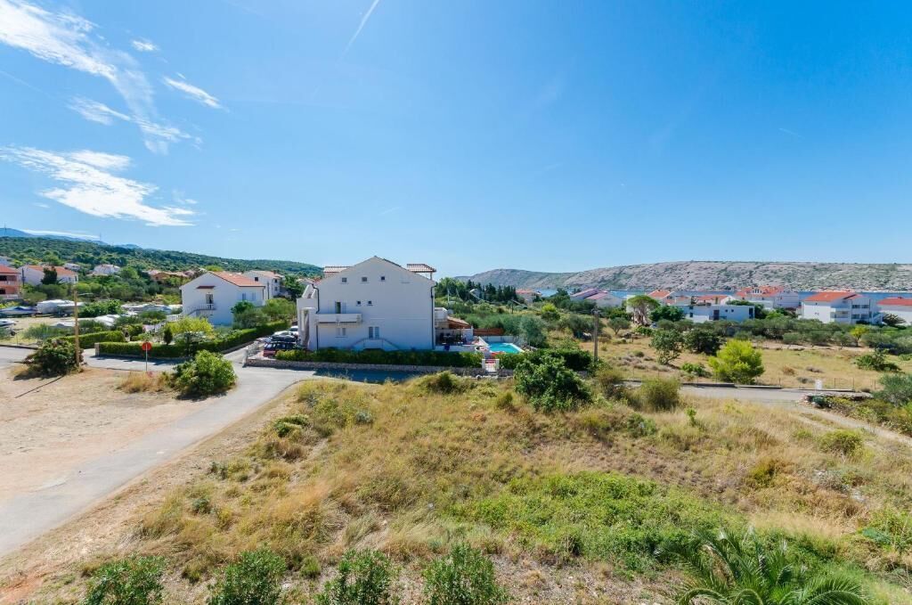 A residential area with houses, a road, and a hilly landscape in the background.