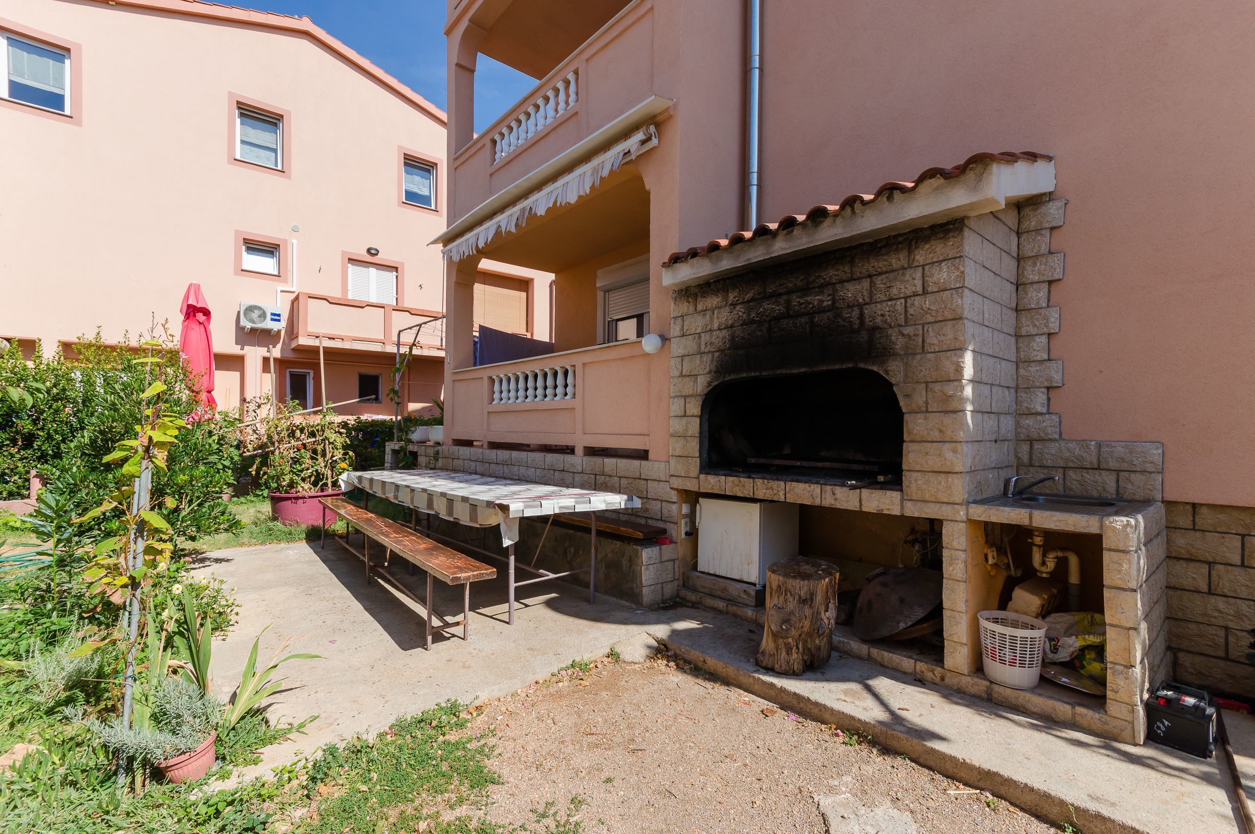 An outdoor patio with a brick oven, a table, and benches.