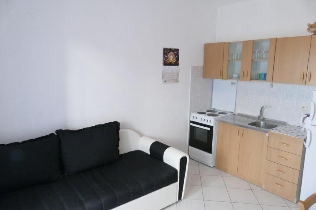 Un espacio habitable compacto con kitchenette, un sofá y una pequeña mesa de comedor.