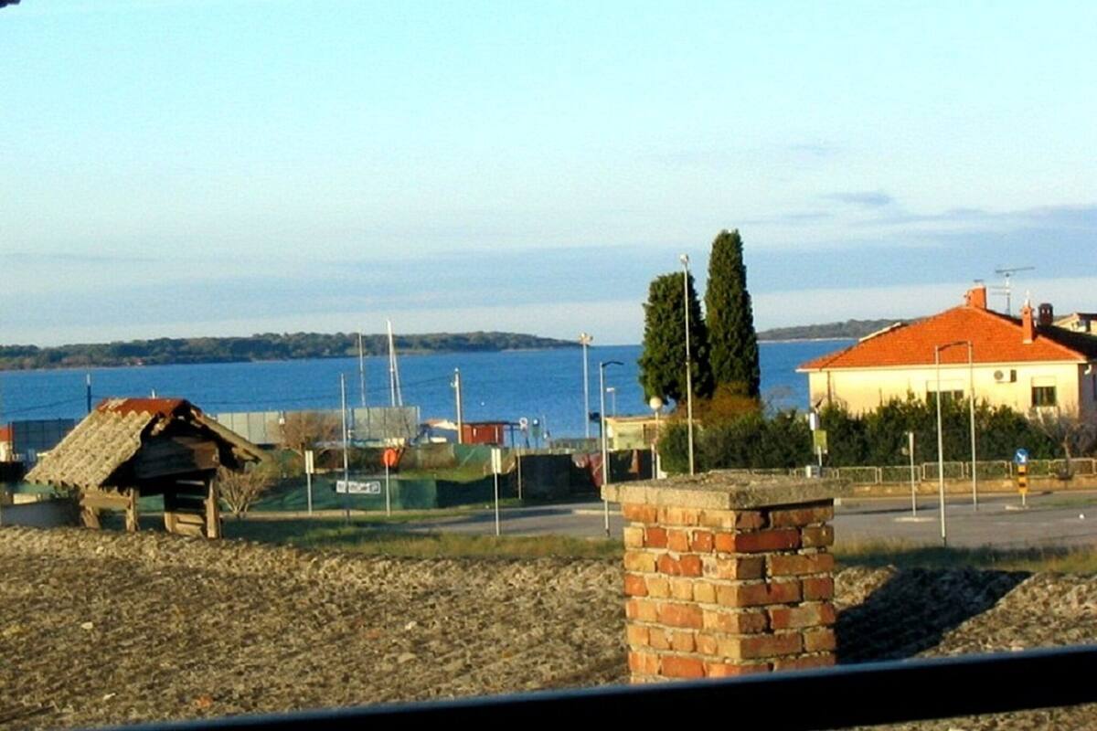A coastal view with a house, a small wooden structure, and a brick wall.