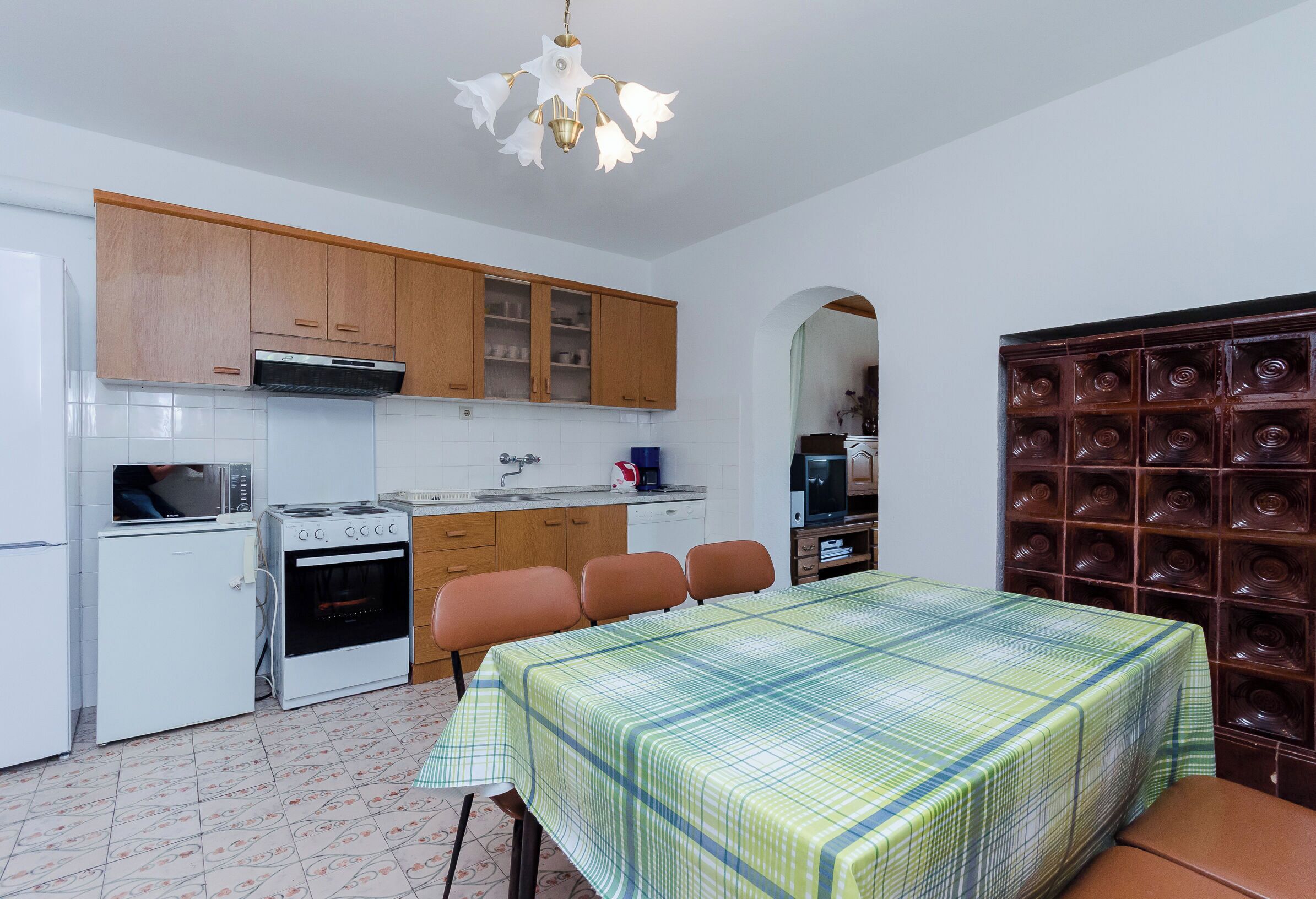 Cocina compacta con armarios de madera, microondas, estufa y comedor con mesa y sillas.