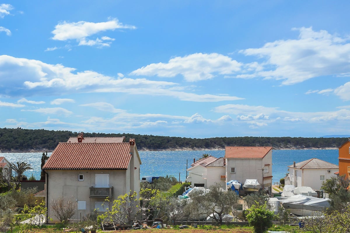 A coastal residential area with houses, a clear blue sky, and a view of the sea.