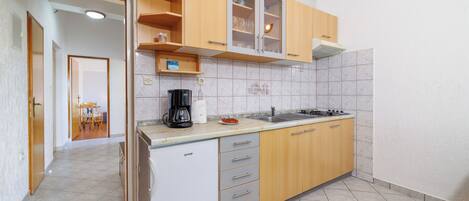 A compact kitchen with wooden cabinets, a built-in dishwasher, and a tiled backsplash.