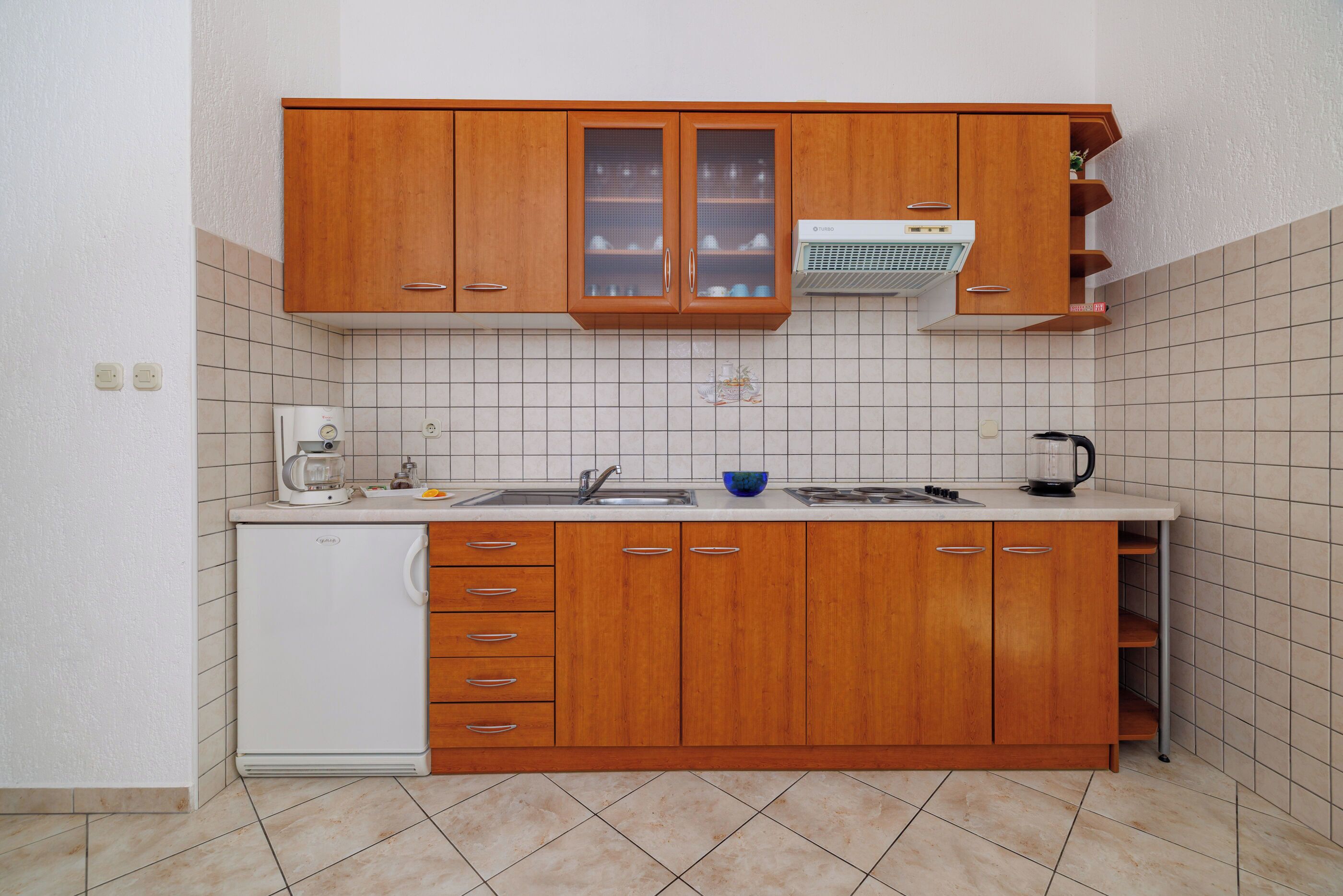 Cocina compacta con armarios de madera, lavavajillas integrado y salpicadero de azulejos.