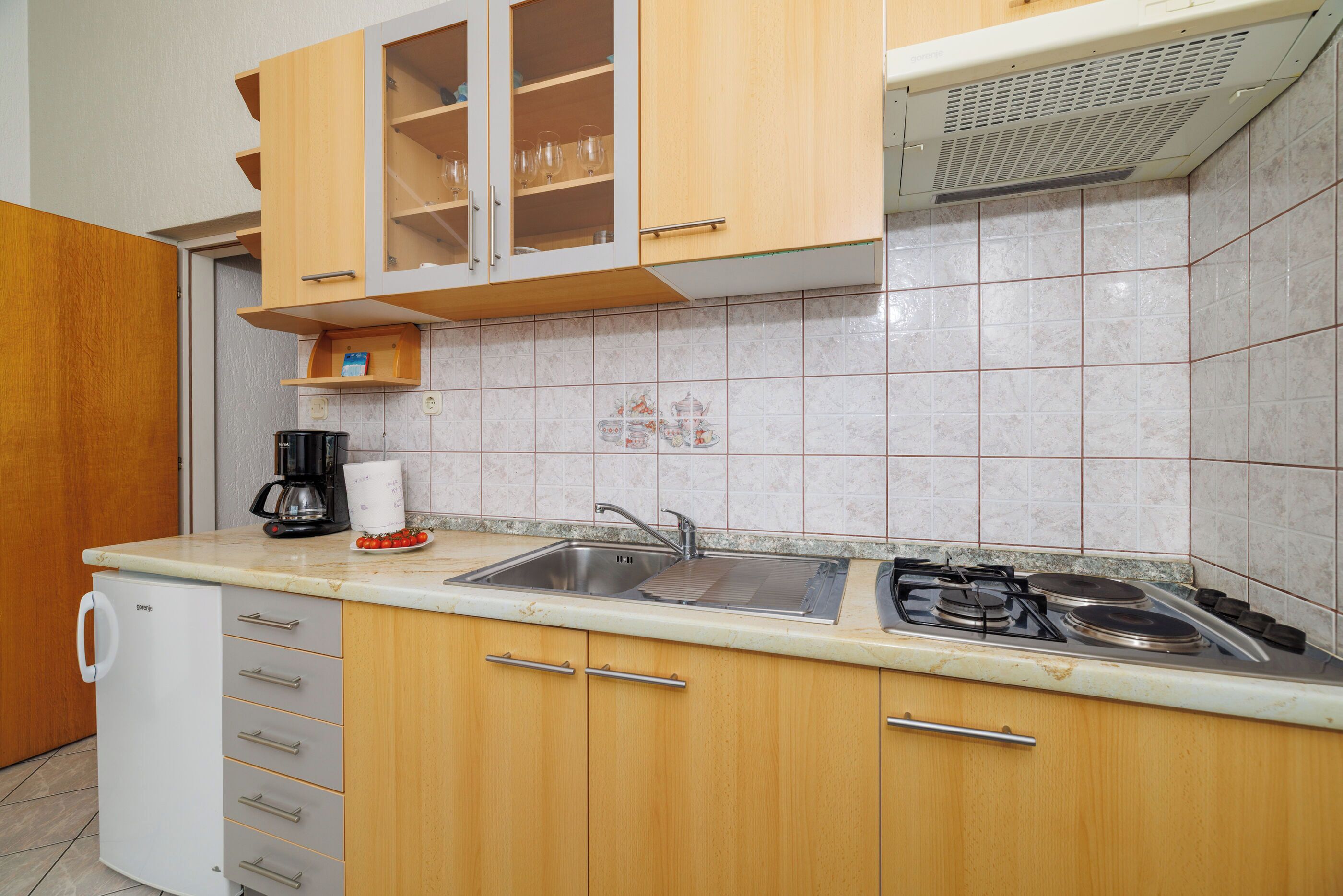 A kitchen with wooden cabinets, a sink, a stove, and a coffee maker.