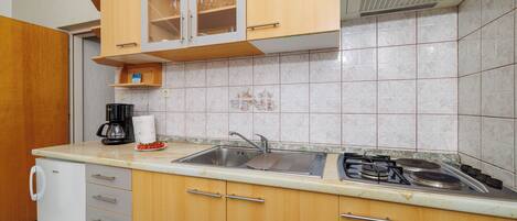 A kitchen with wooden cabinets, a sink, a stove, and a coffee maker.