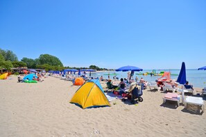 Μια παραλία με σκηνές, ομπρέλες και ανθρώπους που χαλαρώνουν.