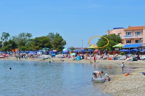 Een strand met parasols en mensen.