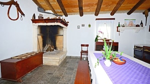 A rustic room with a fireplace, wooden bench, and a dining table with a purple tablecloth. - Apartment Srblin (Zminj)