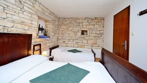 A room with two beds, stone walls, a wooden door, and a small window. - Apartment Srblin (Zminj)