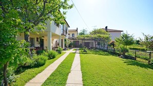 A residential property with a well-maintained lawn, a paved pathway, and a two-story house with a balcony. - Apartment Srblin (Zminj)