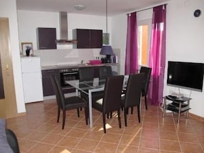 Un espace de vie compact comprenant une kitchenette, un coin repas et un téléviseur.