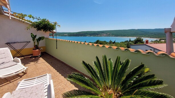 A balcony with a view of a lake, a chair, and a potted plant. - Apartments Marica (Cizici)