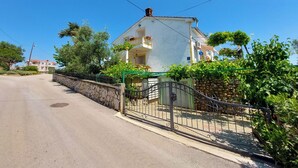 A two-story house with a balcony, surrounded by greenery and a stone wall. - Apartments Marica (Cizici)